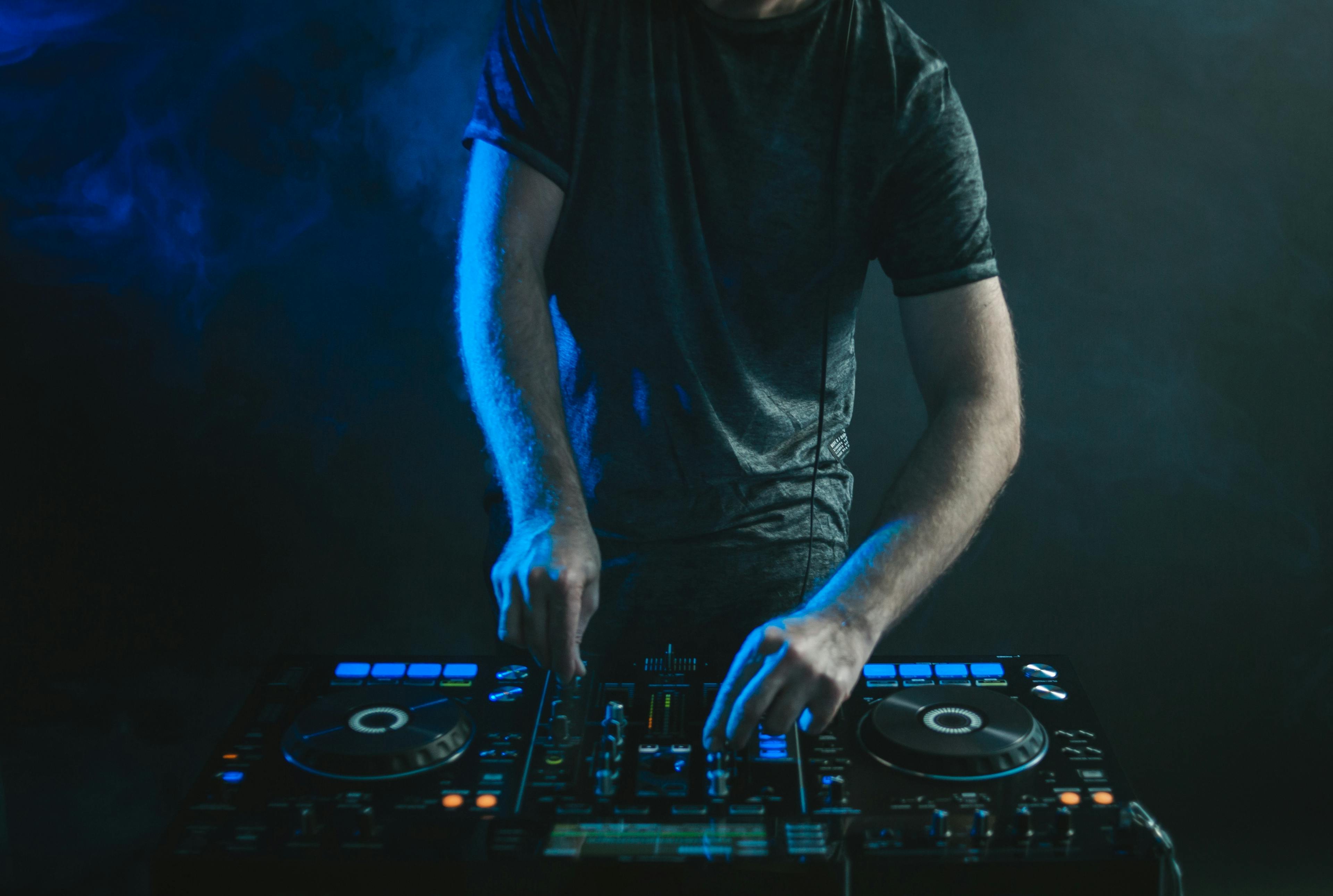 Coverbild von einem DJ mit Lichtern und Rauch